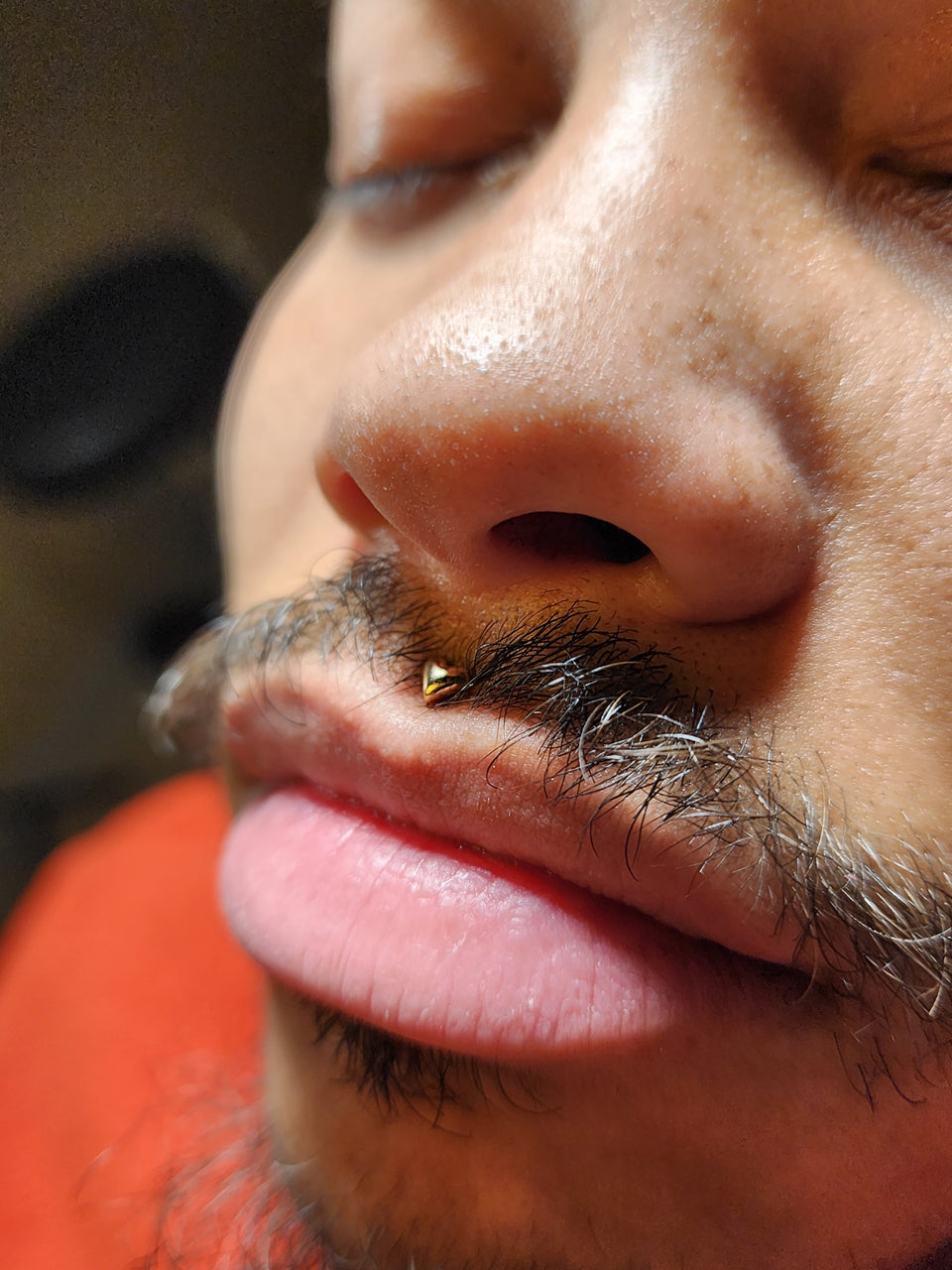 Small gold-toned jewelry end worn in a nostril piercing