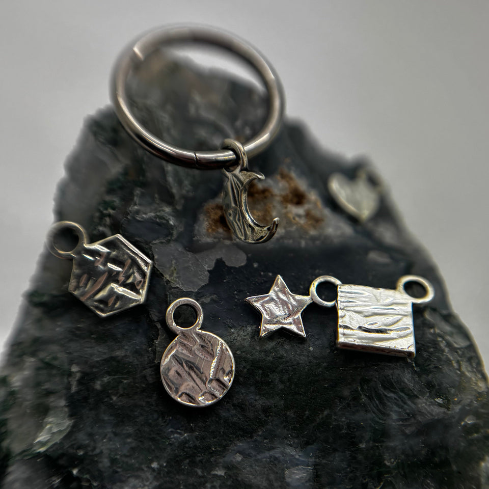 Silver geometric charms and a ring with a hanging charm