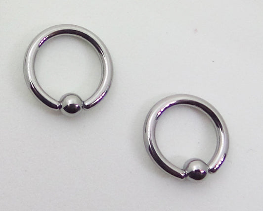 Two polished captive bead rings on a pale background