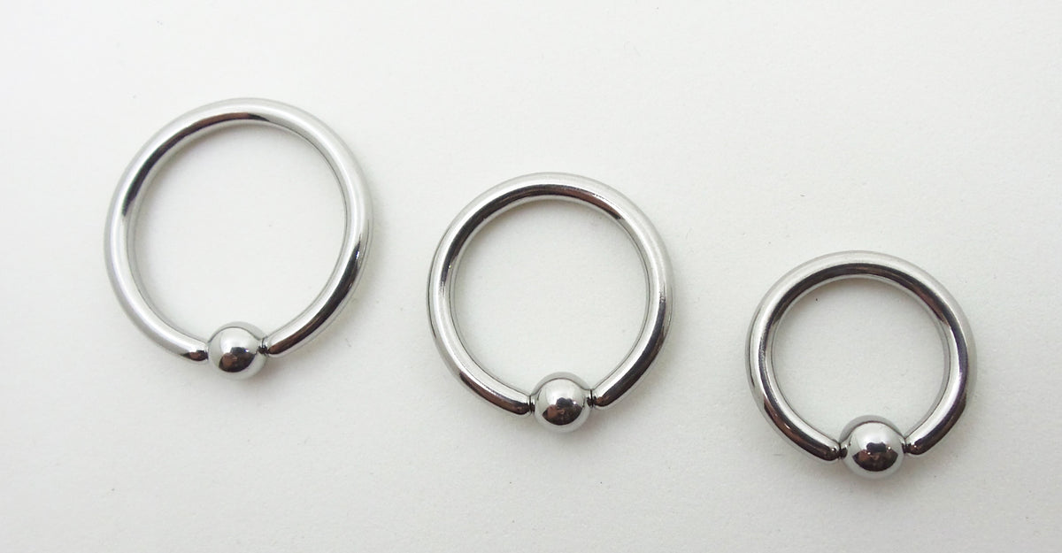 Three polished titanium captive bead rings