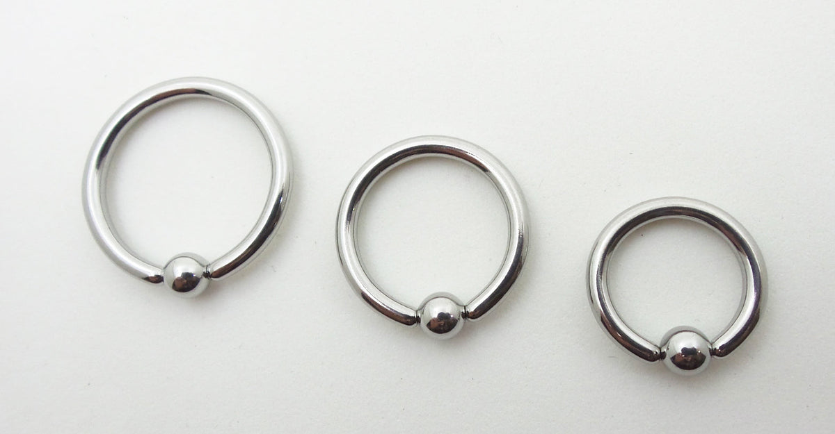 Three polished titanium captive bead rings