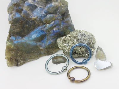 Titanium captive bead rings displayed against natural stone