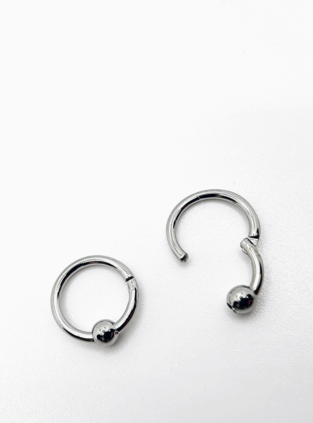 Polished titanium captive bead rings shown open and closed