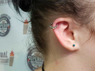Polished titanium clicker in an upper-ear piercing