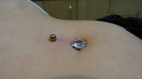 Freshly pierced navel with our implant grade titanium Curved barbell with a pear shaped clear cubic zirconia in the center and the bar anodized to a gold tone