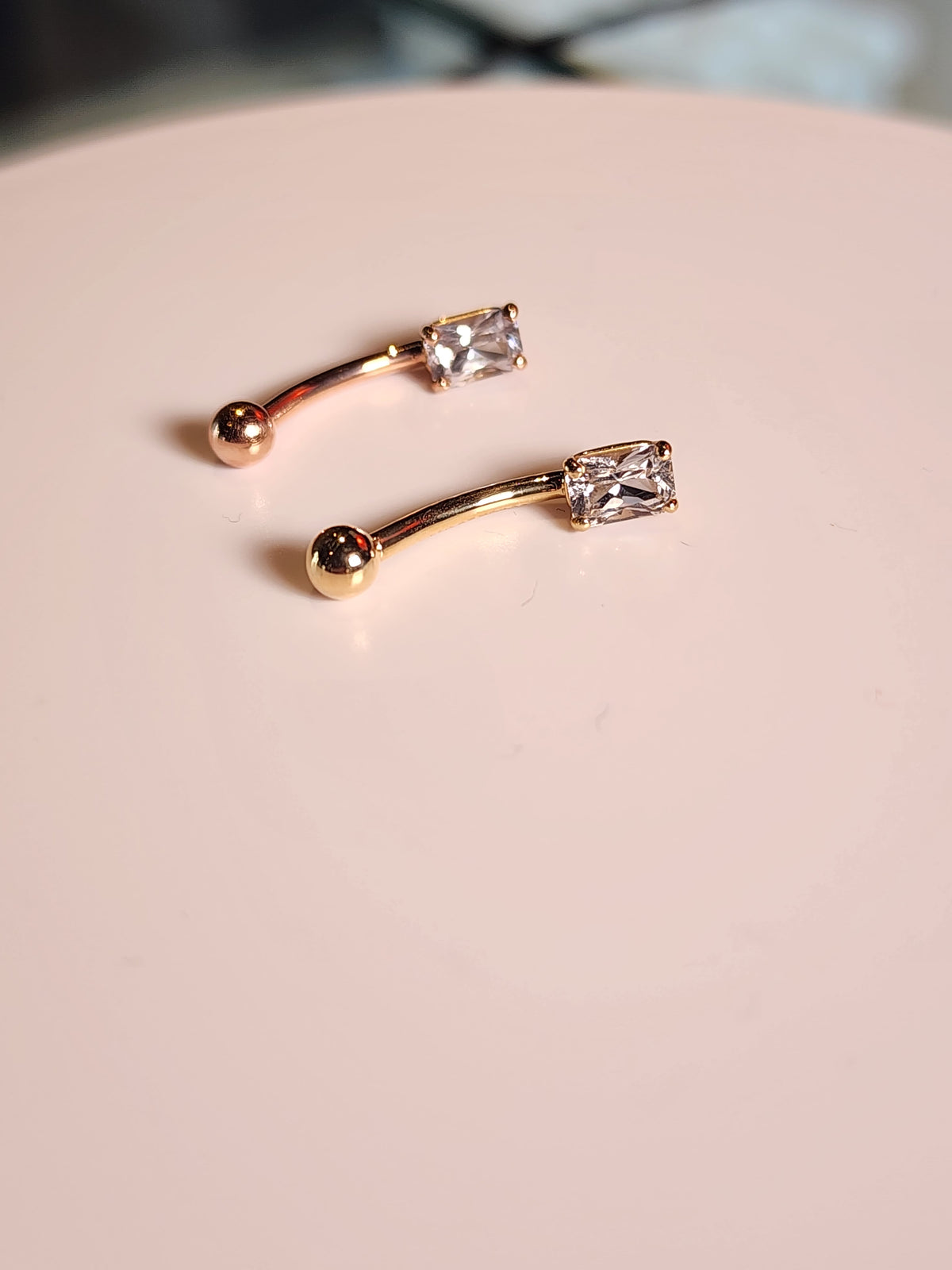 Yellow and rose gold curved navel barbells with white sapphire ends