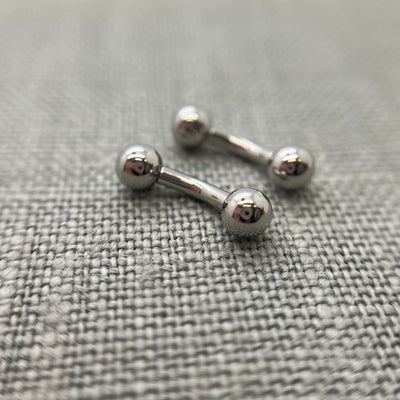 Polished stainless steel curved barbells on grey fabric