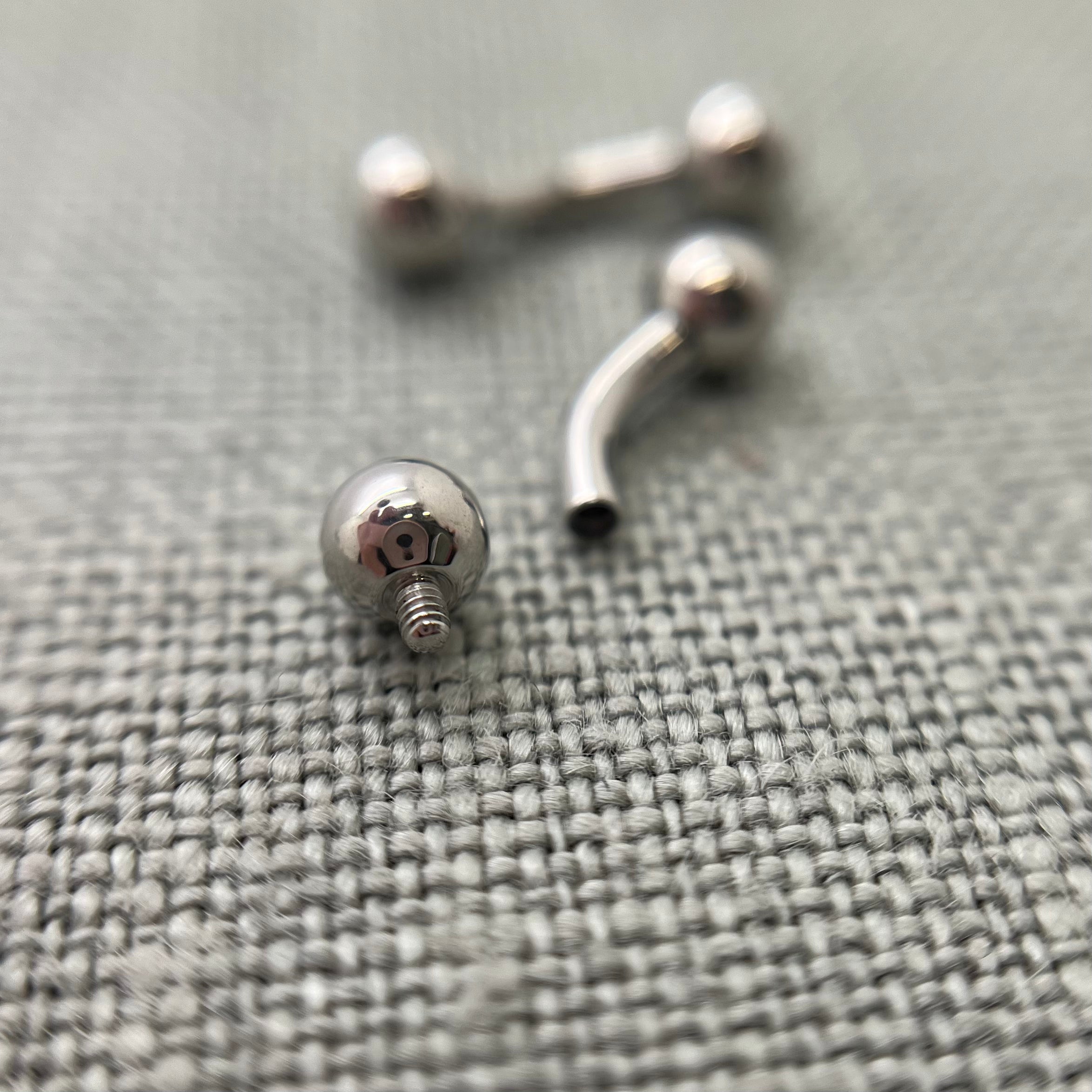 Polished stainless steel curved barbells on grey fabric