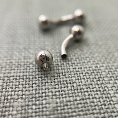 Polished stainless steel curved barbells on grey fabric