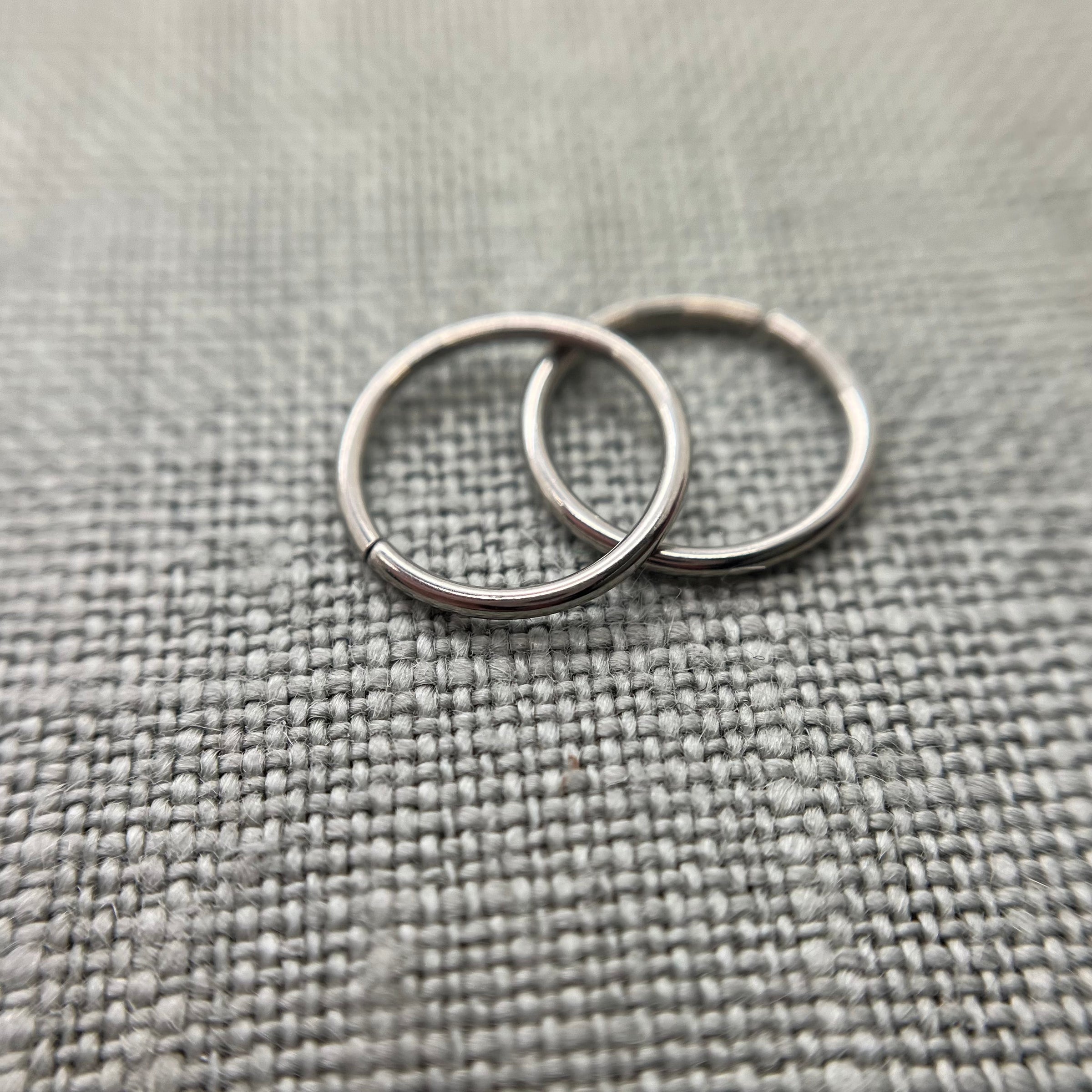 Two polished stainless steel seam rings on grey fabric