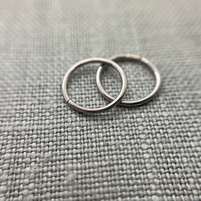 Two polished stainless steel seam rings on grey fabric