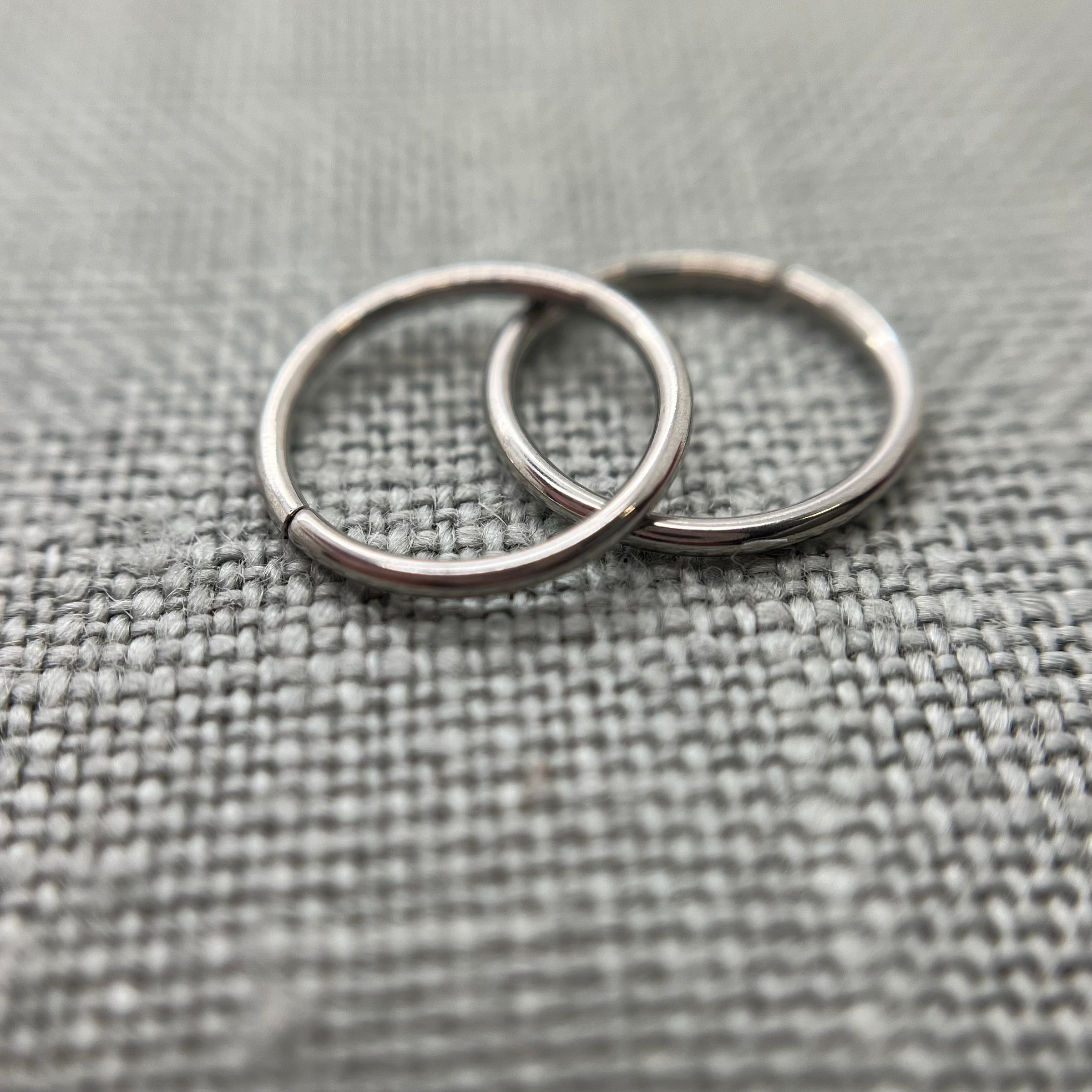 Two polished stainless steel seam rings on grey fabric