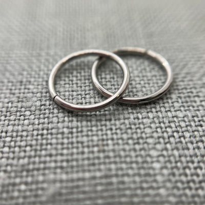 Two polished stainless steel seam rings on grey fabric