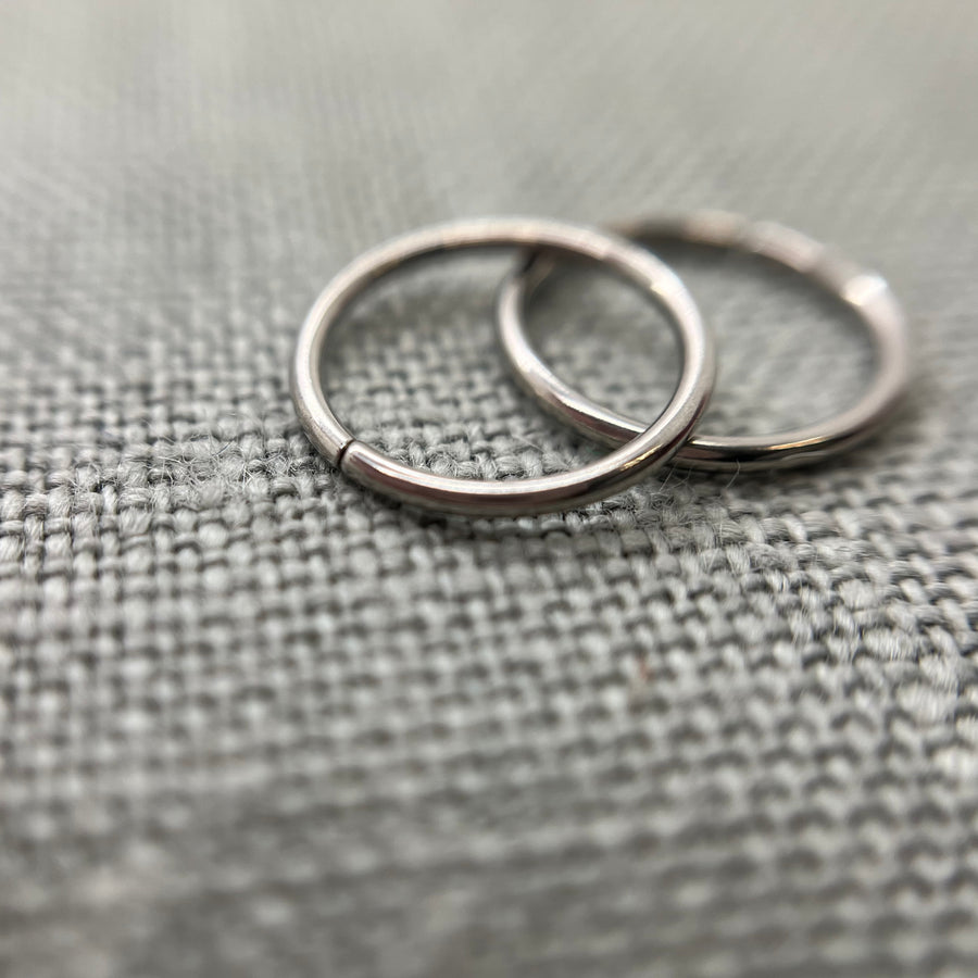 Two polished stainless steel seam rings on grey fabric