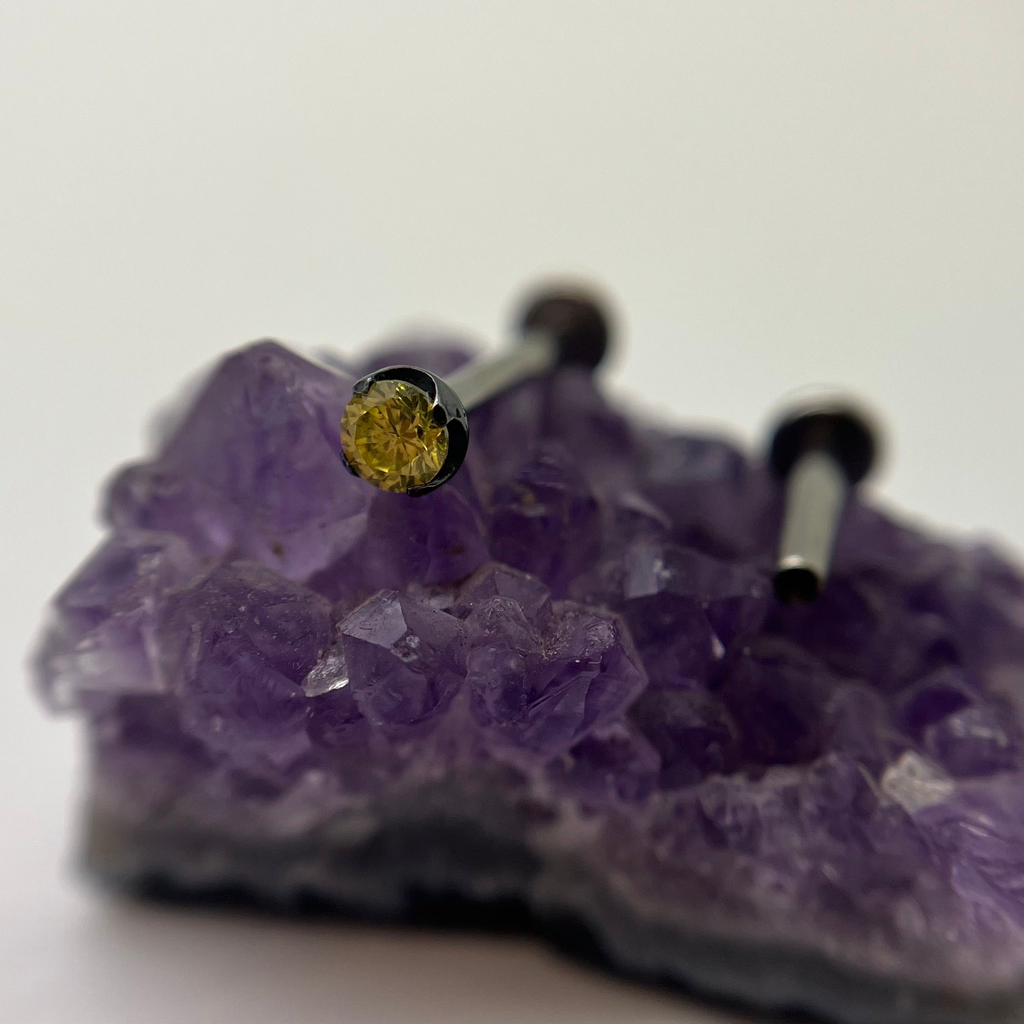 Yellow cubic zirconia in a black niobium setting on purple crystal