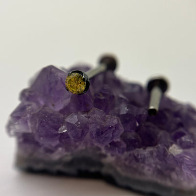 Yellow cubic zirconia in a black niobium setting on purple crystal