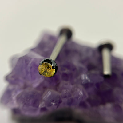 Yellow cubic zirconia in a black niobium setting on purple crystal
