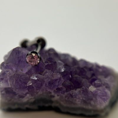 Pink cubic zirconia in a black niobium setting on purple crystal