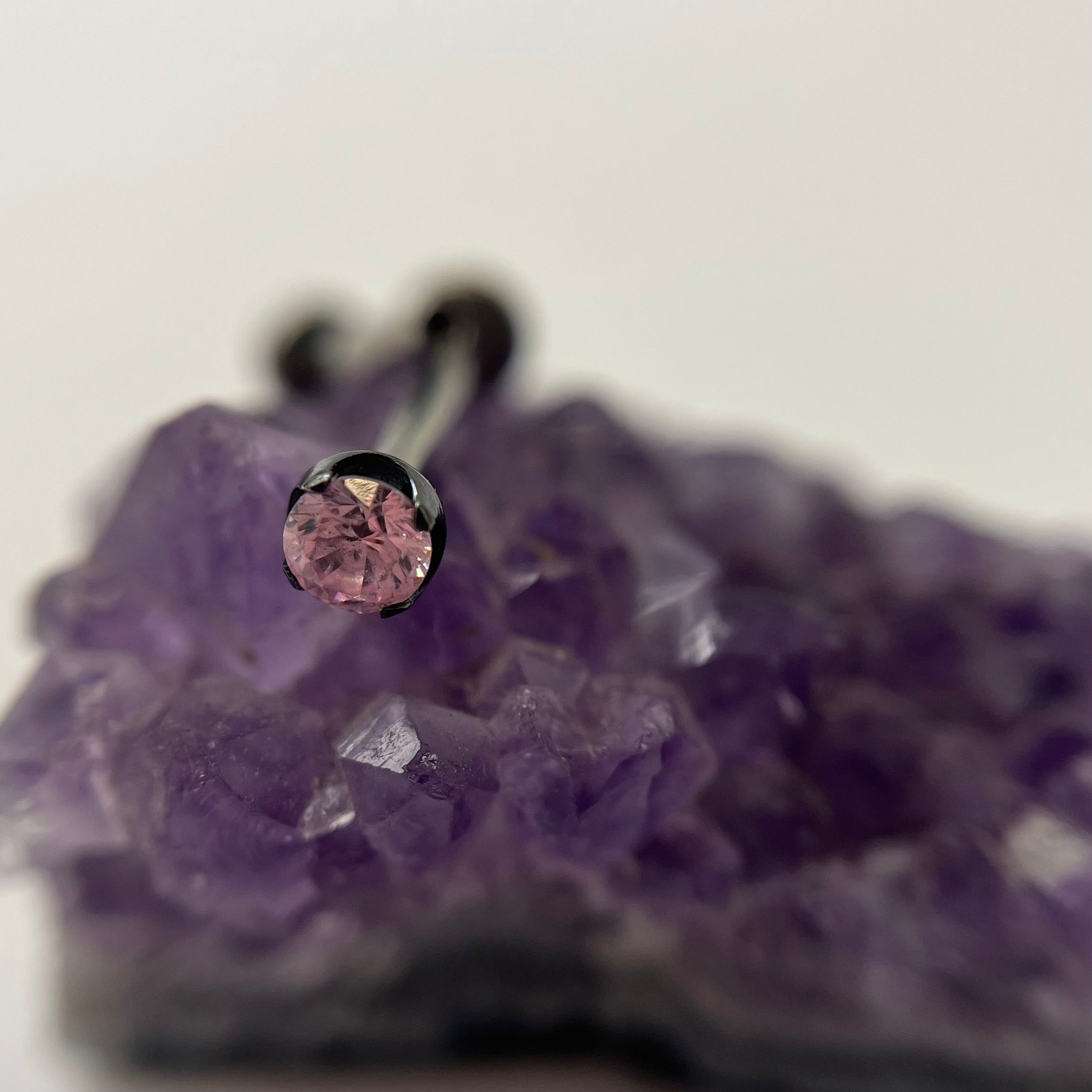 Pink cubic zirconia in a black niobium setting on purple crystal