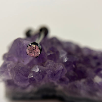 Pink cubic zirconia in a black niobium setting on purple crystal
