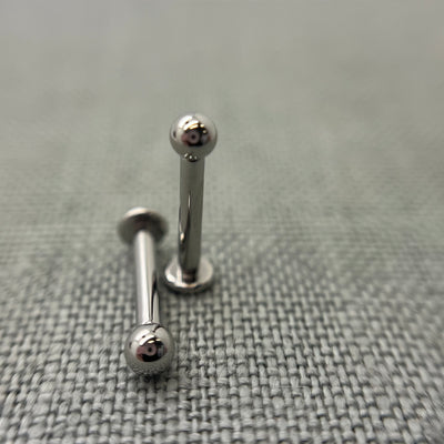 Two stainless steel flat-back labrets with round beads
