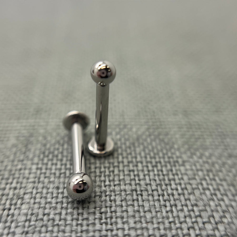 Two stainless steel flat-back labrets with round beads
