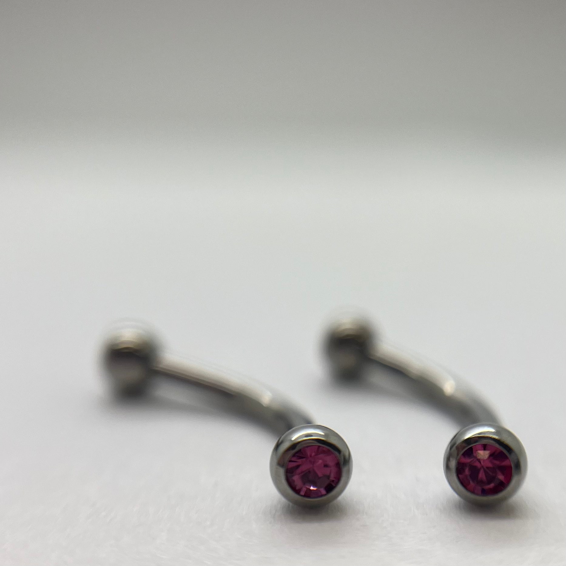 Stainless steel curved barbells with pink cubic zirconia ends