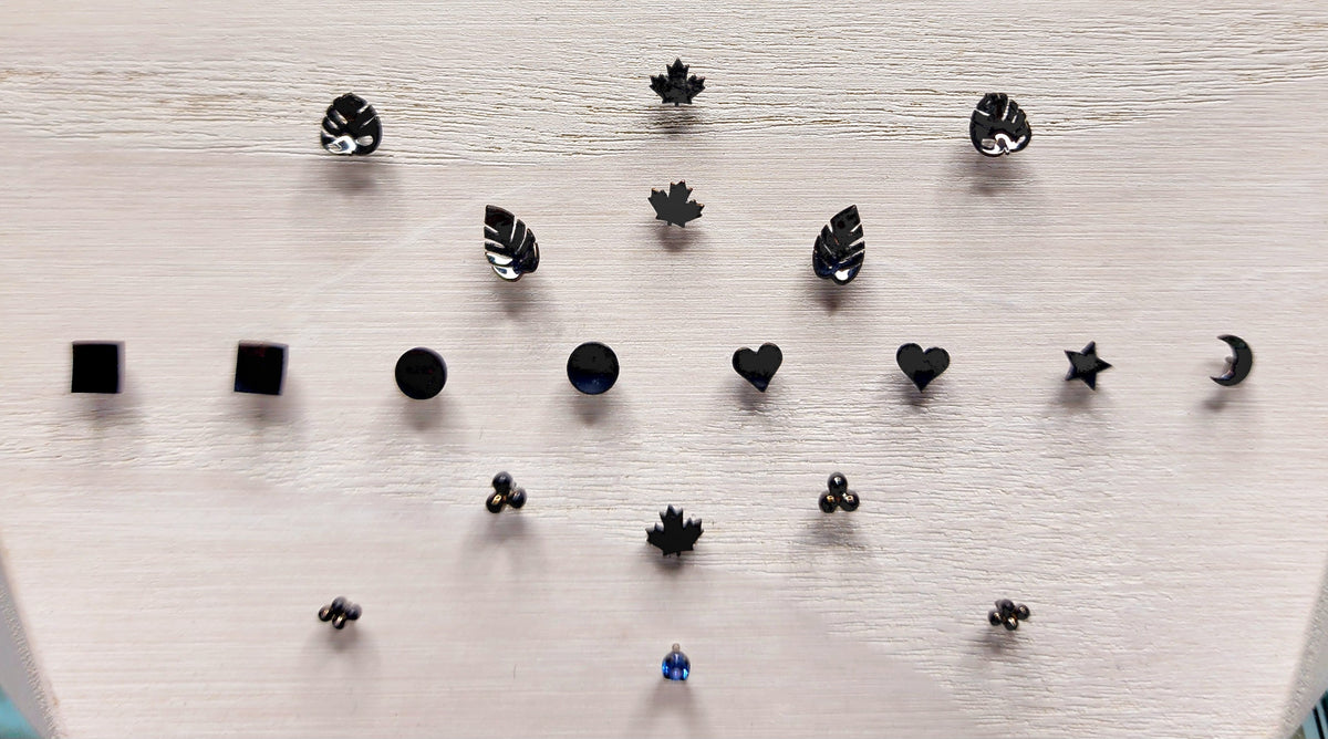 Black rhodium-plated gold jewelry ends in leaf, heart and geometric shapes