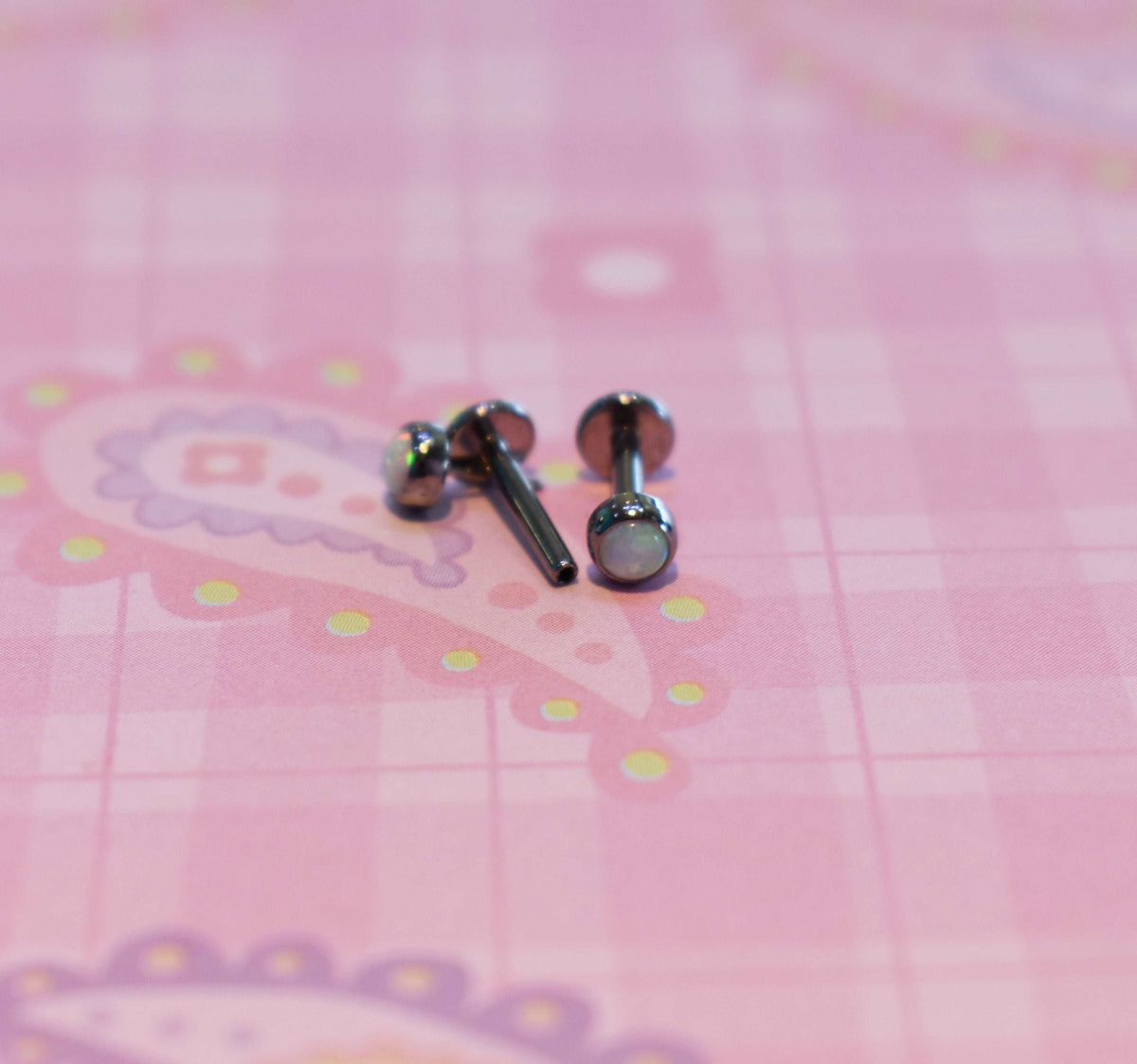 Flat-back jewelry posts and decorative ends on a pink surface
