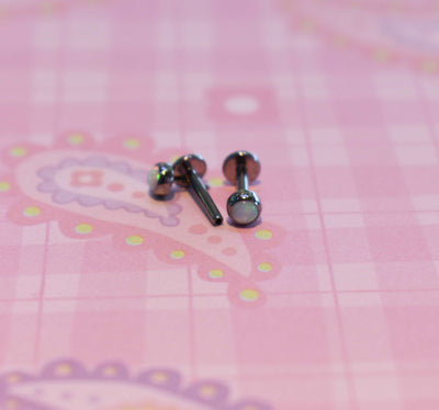 Flat-back jewelry posts and decorative ends on a pink surface
