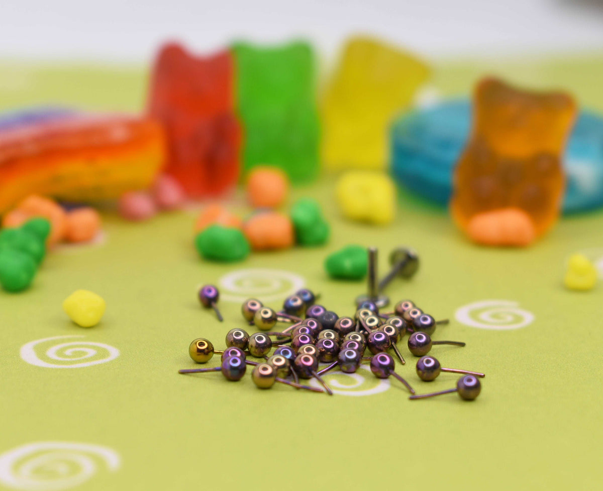 Pink anodized jewelry pieces beside colourful candy props