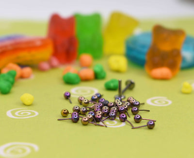 Pink anodized jewelry pieces beside colourful candy props