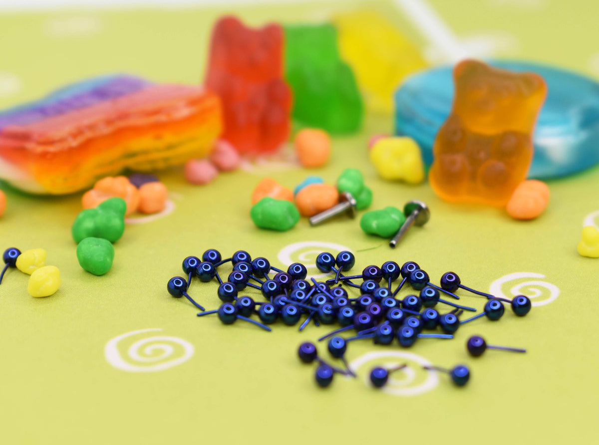 Blue anodized jewelry pieces beside colourful candy props