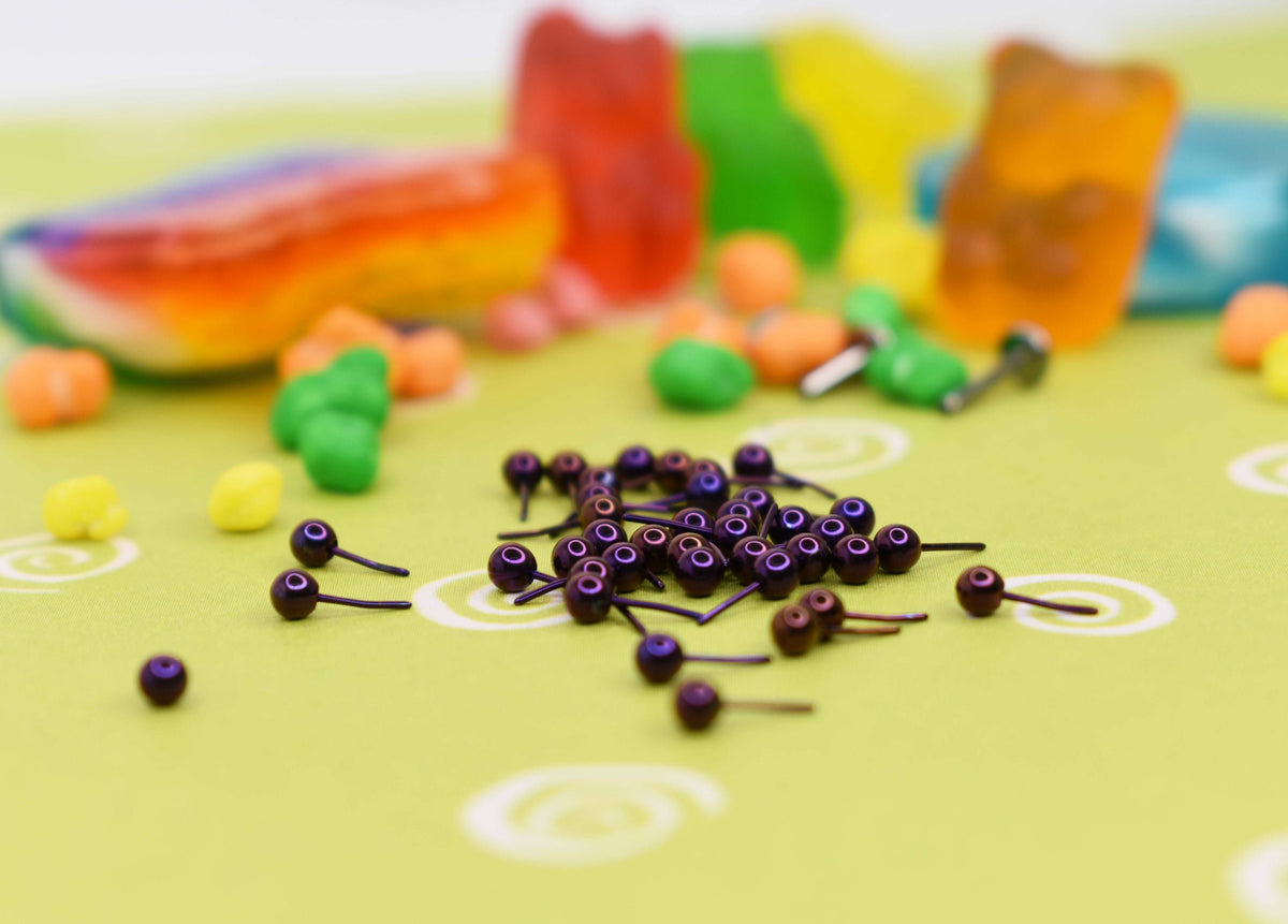 Purple anodized jewelry pieces beside colourful candy props