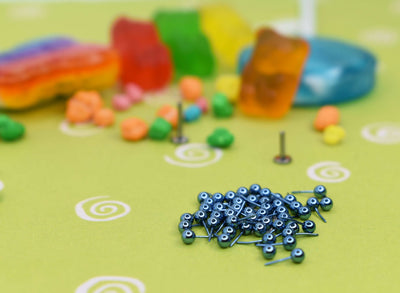 Light blue anodized jewelry pieces beside colourful candy props