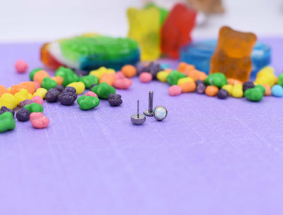 Flat-back jewelry posts and small decorative ends on a purple surface