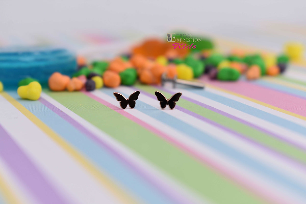 Small gold cross-shaped jewelry ends on a pastel striped surface