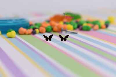 Small gold cross-shaped jewelry ends on a pastel striped surface