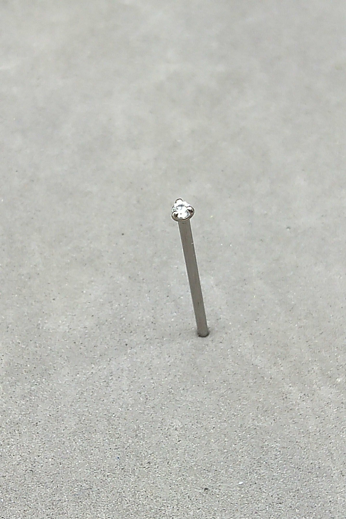 Straight titanium nostril stud with a clear prong-set gemstone