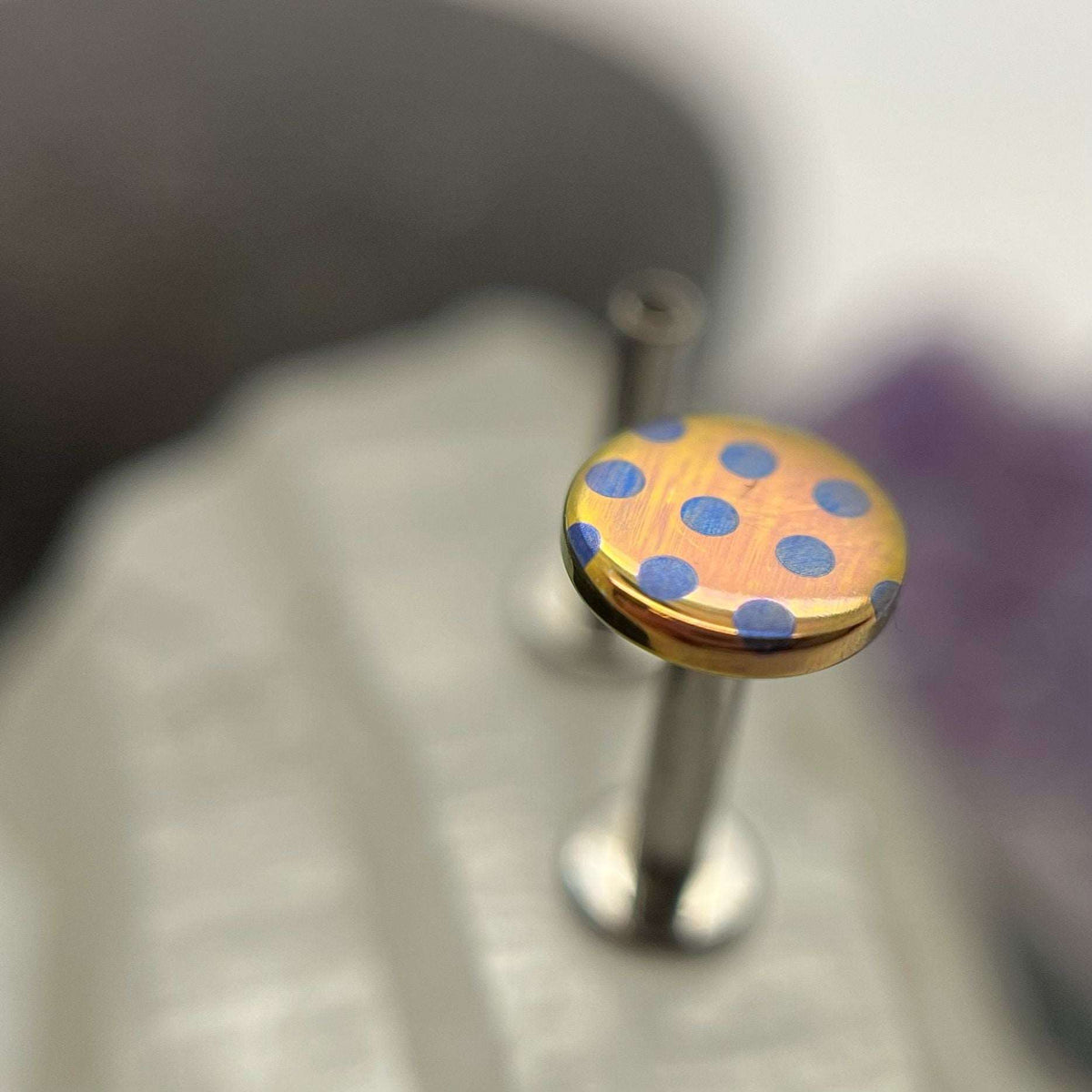 Peach titanium disc with blue polka dots on a flat-back post