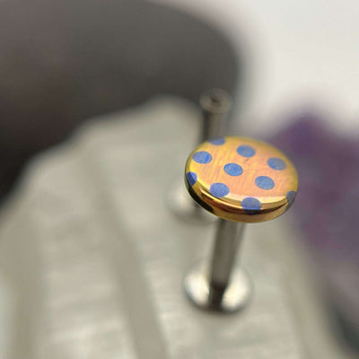 Peach titanium disc with blue polka dots on a flat-back post