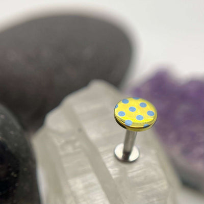 Yellow titanium disc with blue polka dots on a flat-back post