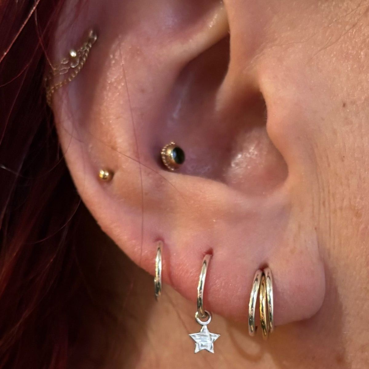 Curated ear with gemstone studs, hoops and a dangling star charm
