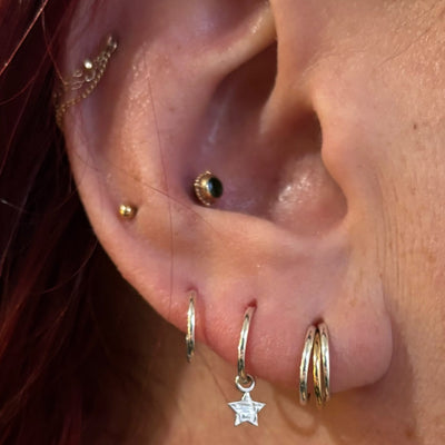Curated ear with gemstone studs, hoops and a dangling star charm