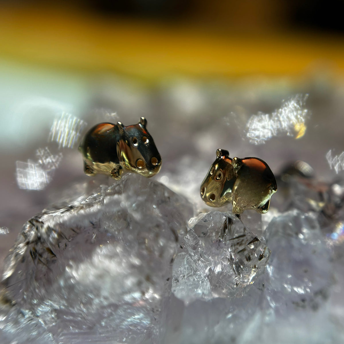 Small yellow gold hippo-shaped jewelry ends on textured stone
