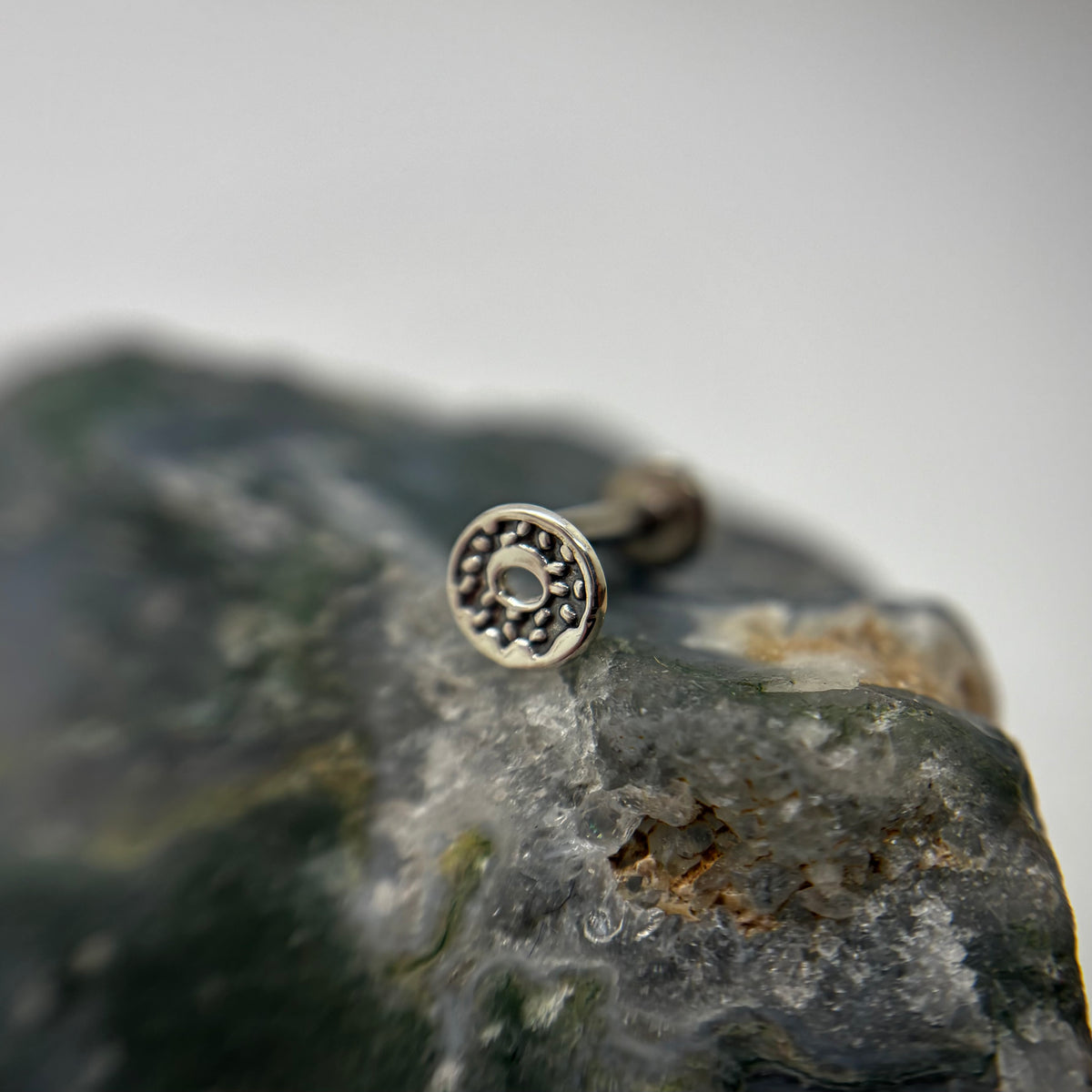 Silver sprinkled doughnut-shaped jewelry end on a flat-back post