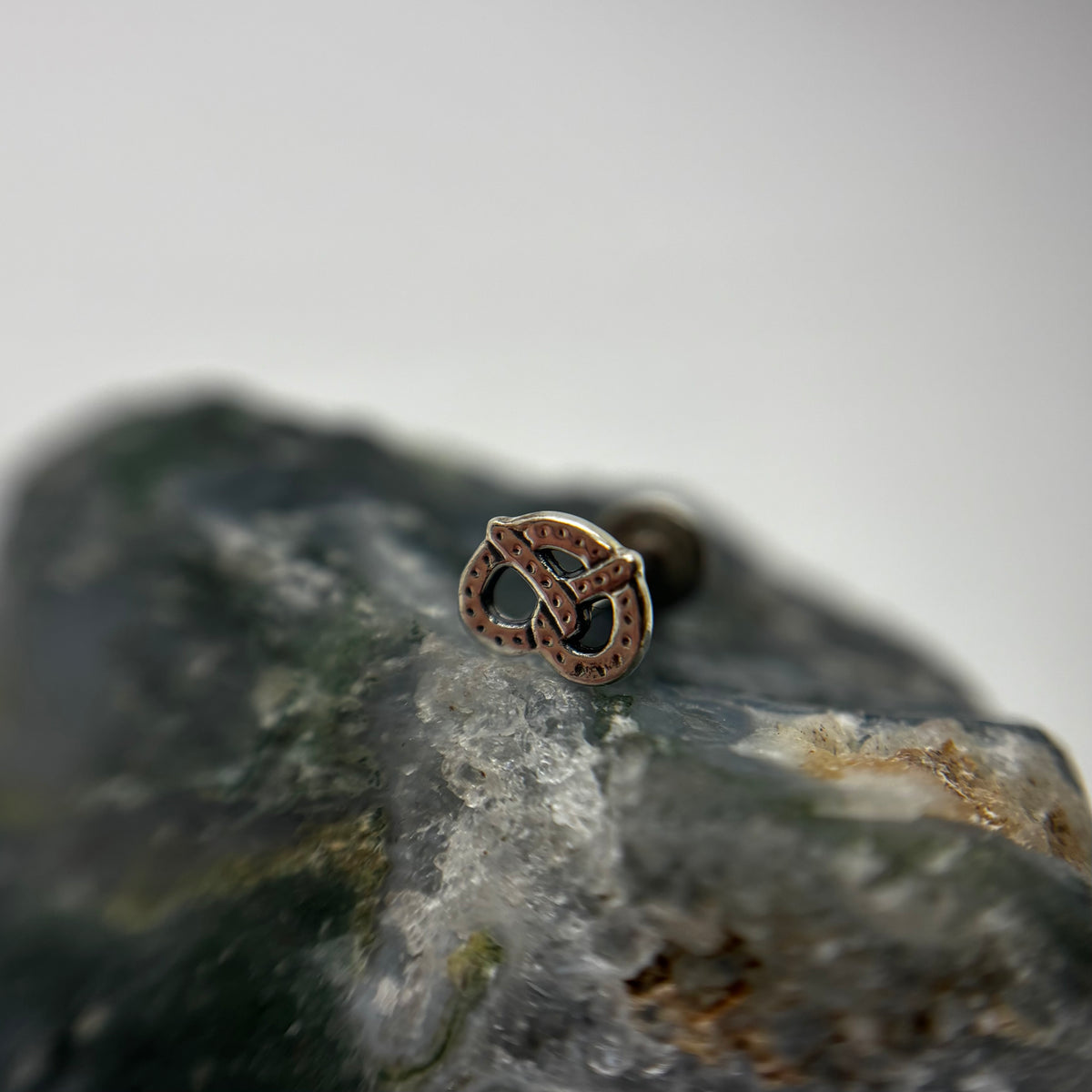 Silver pretzel-shaped jewelry end on a flat-back post