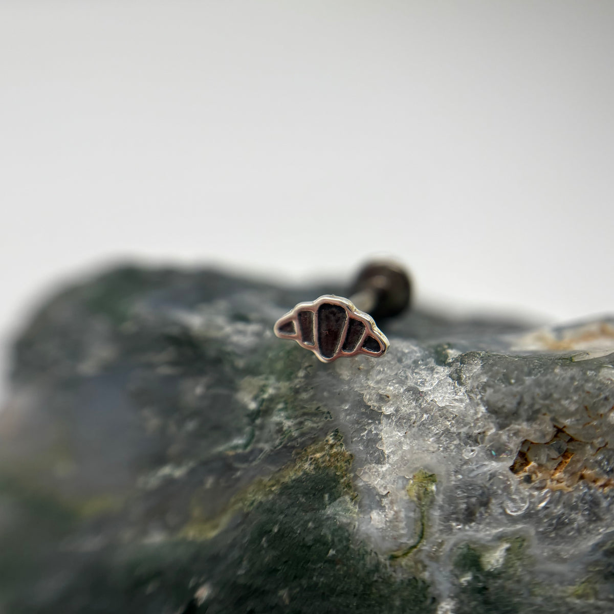 Silver croissant-shaped jewelry end on a flat-back post