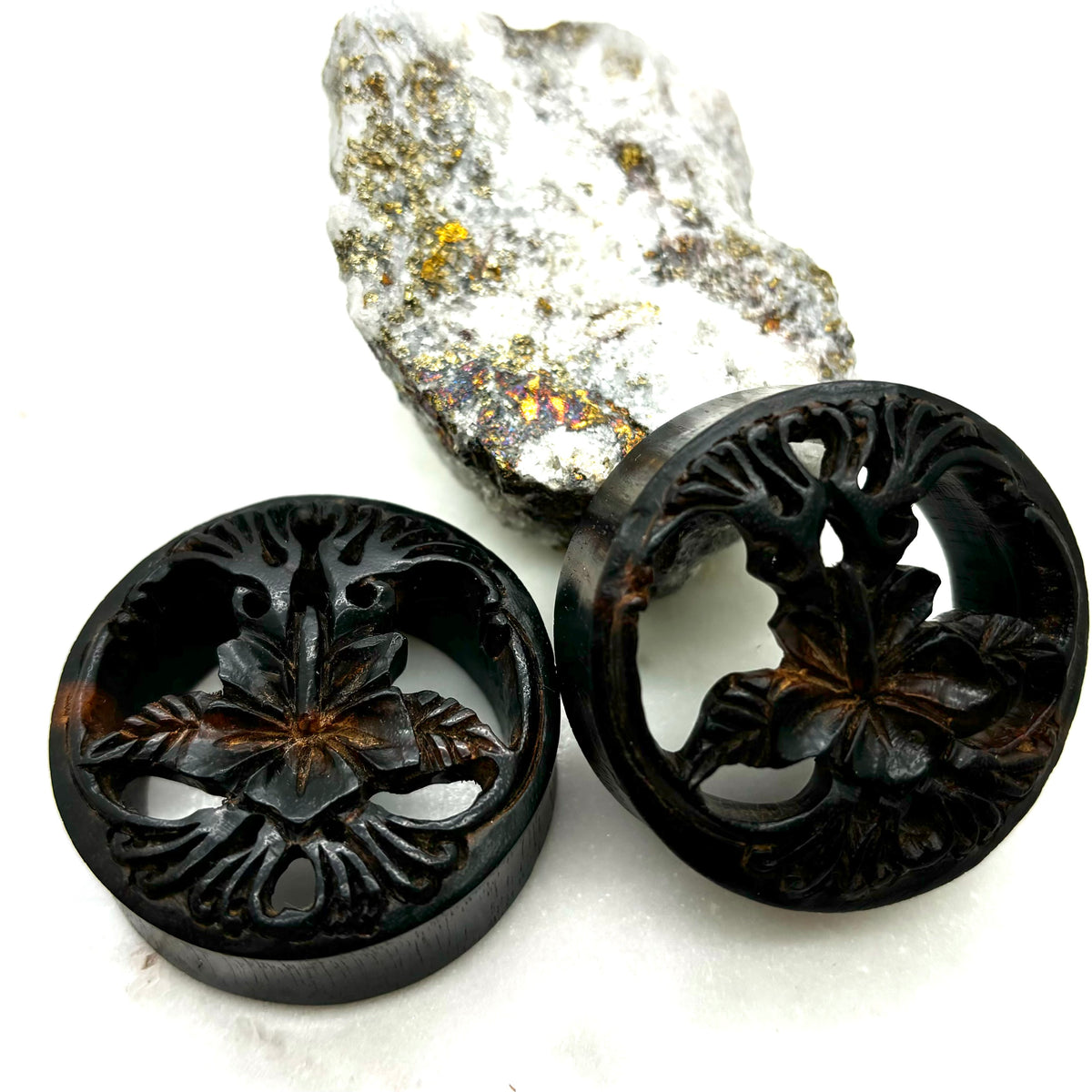 Carved dark wood double-flare plugs with an open tree design