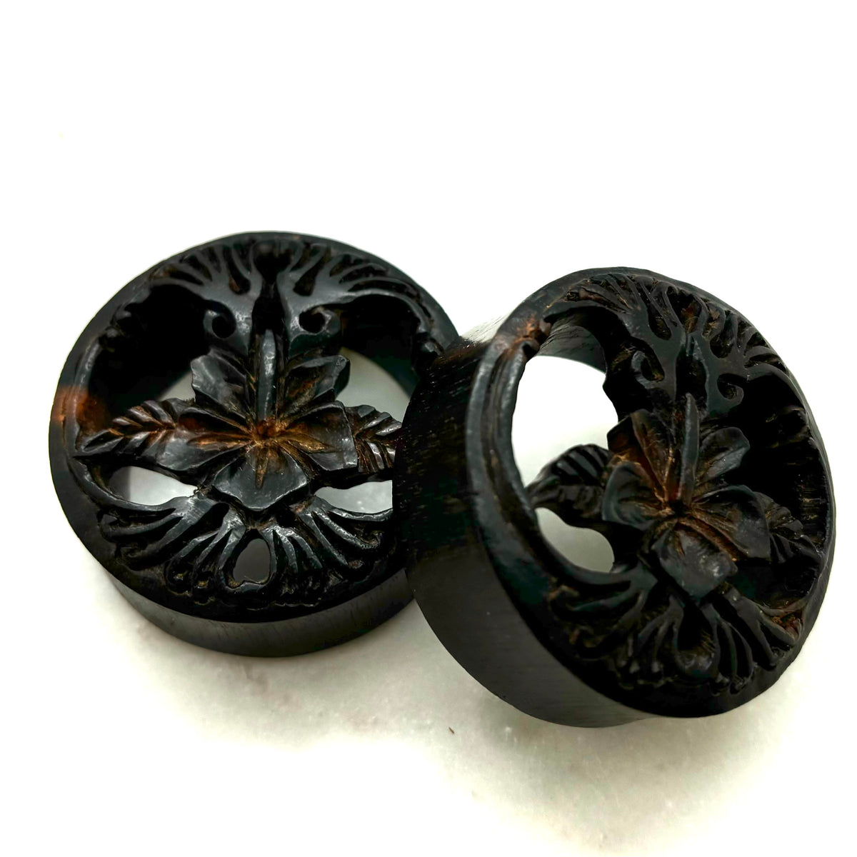 Carved dark wood double-flare plugs with an open tree design